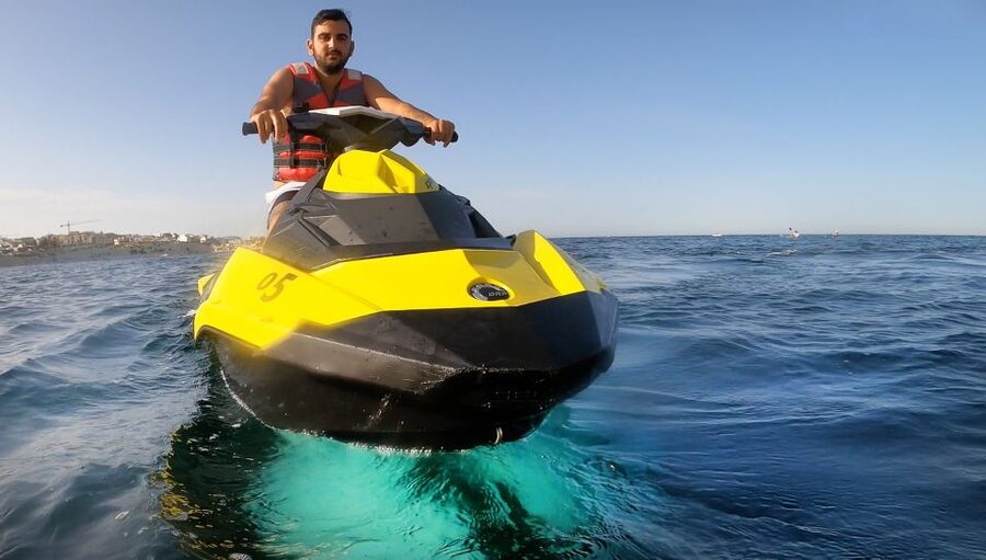 A jet ski lifting off the back of a wave in open blue water